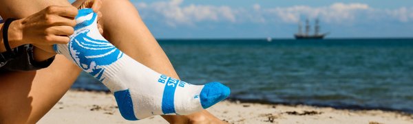 Surfsocken mit Welle Motiv am Strand und Anmeldung Newsletter für nachhaltige Socken